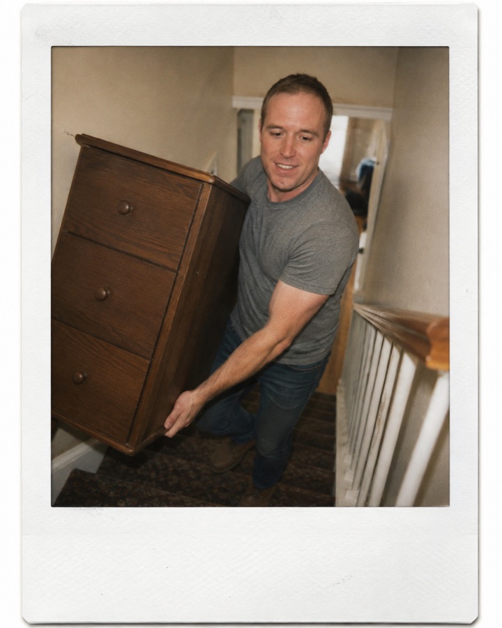 Tim carrying a dresser up a staircase